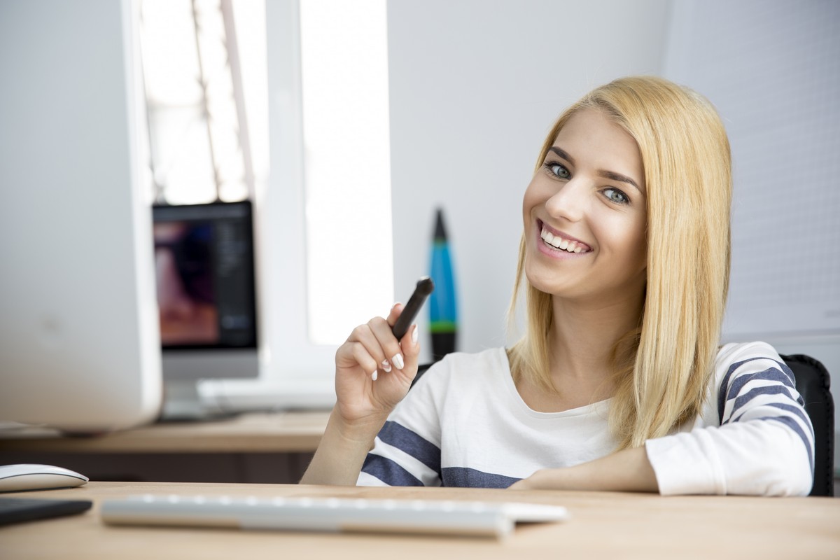 Young woman pointing pen at camera in office